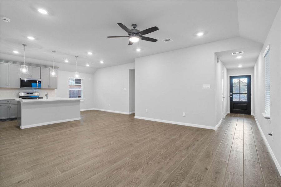 This expansive view from the back of the house showcases a seamless, open-concept layout that creates a warm and inviting path for guests, drawing the eye past the heart of the home toward the welcoming front entryway