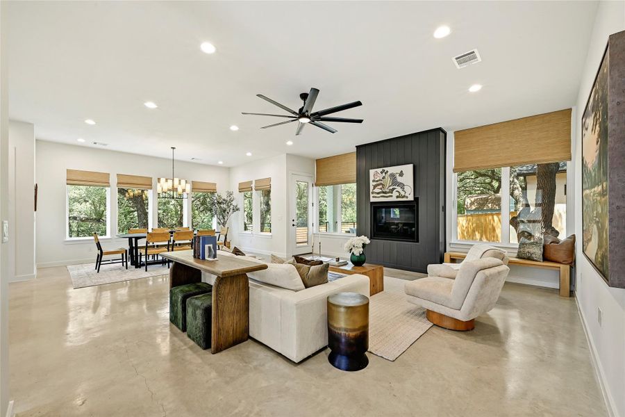 Open-concept living room connects kitchen, dining, and living in one uninterrupted space anchored by natural light and tree views. Open-concept living room connects kitchen, dining, and living in one uninterrupted space anchored by natural light and tree views.