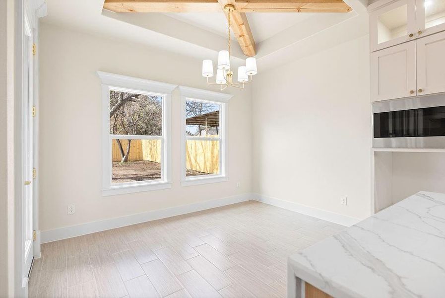 Unfurnished dining area with a chandelier, light wood finished floors, and baseboards