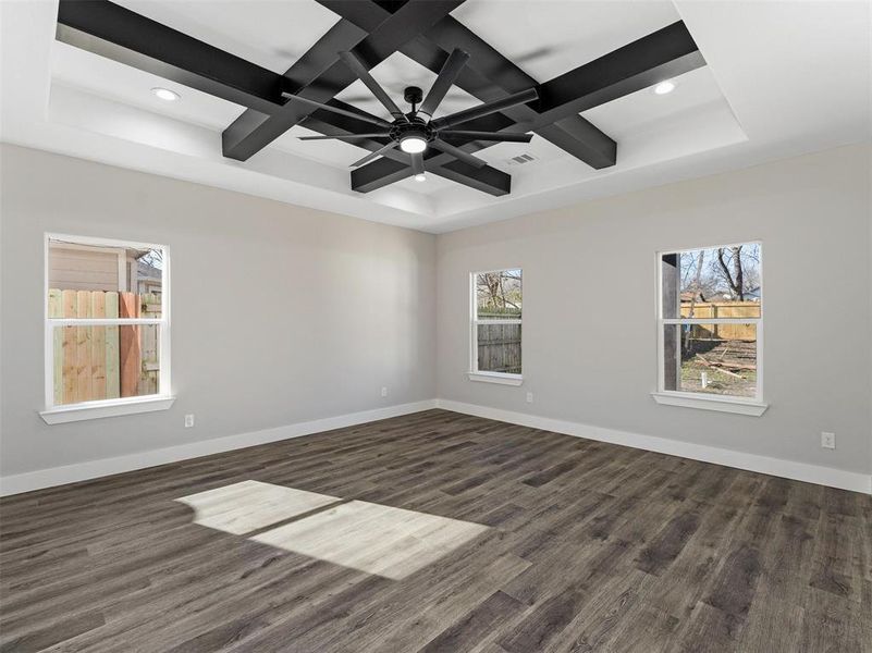 Spare room with ceiling fan, dark hardwood / wood-style flooring, a wealth of natural light, and coffered ceiling