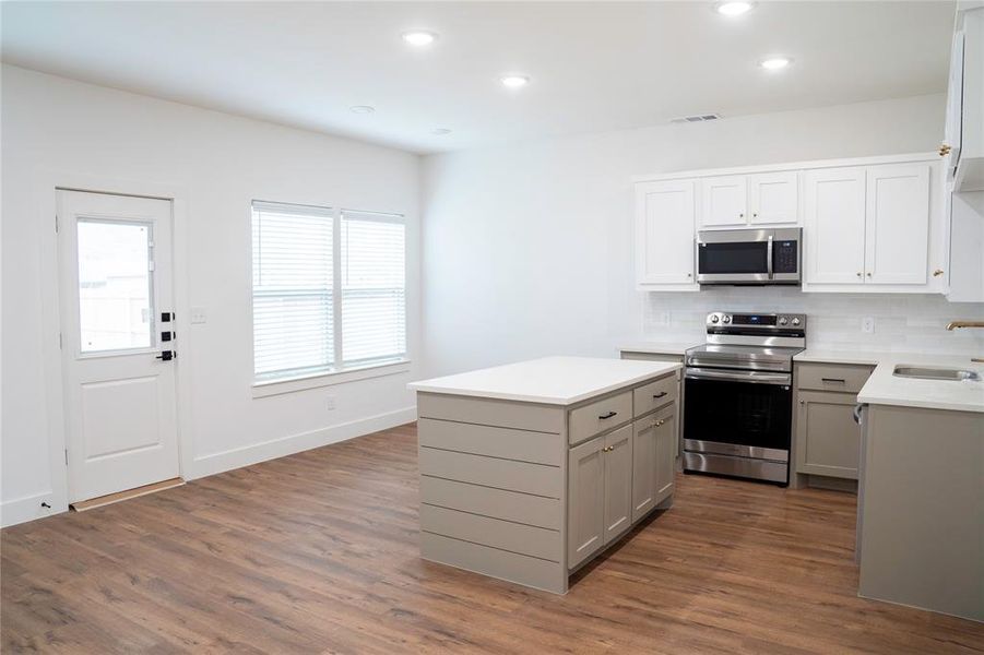 Kitchen featuring appliances with stainless steel finishes, dark hardwood / wood-style floors, gray cabinets, and tasteful backsplash