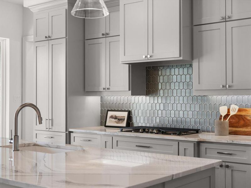 Kitchen with light stone counters, backsplash, gray cabinets, and stainless steel gas stovetop