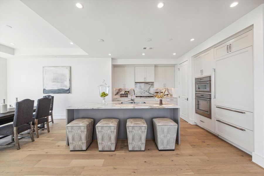 Large kitchen island with porcelain countertops seats four comfortably.  The Sub-Zero integrated refrigerator with cabinet panel fronts blends in and provide a clean look in the kitchen.