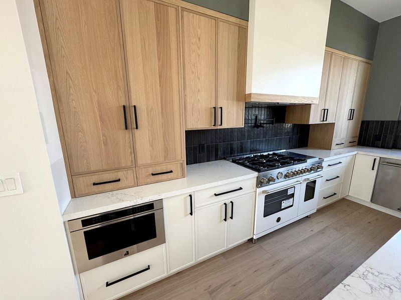 Kitchen featuring stainless steel appliances, light stone countertops, tasteful backsplash, and wall chimney exhaust hood