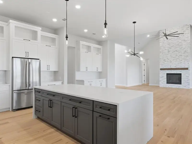 Modern kitchen featuring a large island with a light-toned countertop and dark cabinetry
