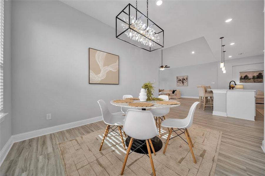 Dining area with light wood-style floors, a ceiling fan, recessed lighting, and a chandelier Dining area with light wood-style floors, a ceiling fan, recessed lighting, and a chandelier