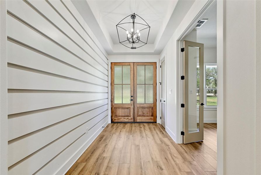 Double mahogany doors open to an inviting entry with shiplap walls and access to the private study.