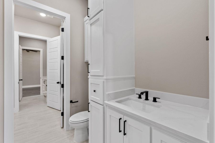 White cabinetry, sleek sink, and modern black fixtures define this refined bathroom. White cabinetry, sleek sink, and modern black fixtures define this refined bathroom.