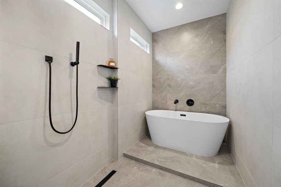 Indulge in luxury with this spa-inspired bathroom featuring a central freestanding bathtub the tile tones add to the serene ambiance, creating the perfect retreat for relaxation and rejuvenation.