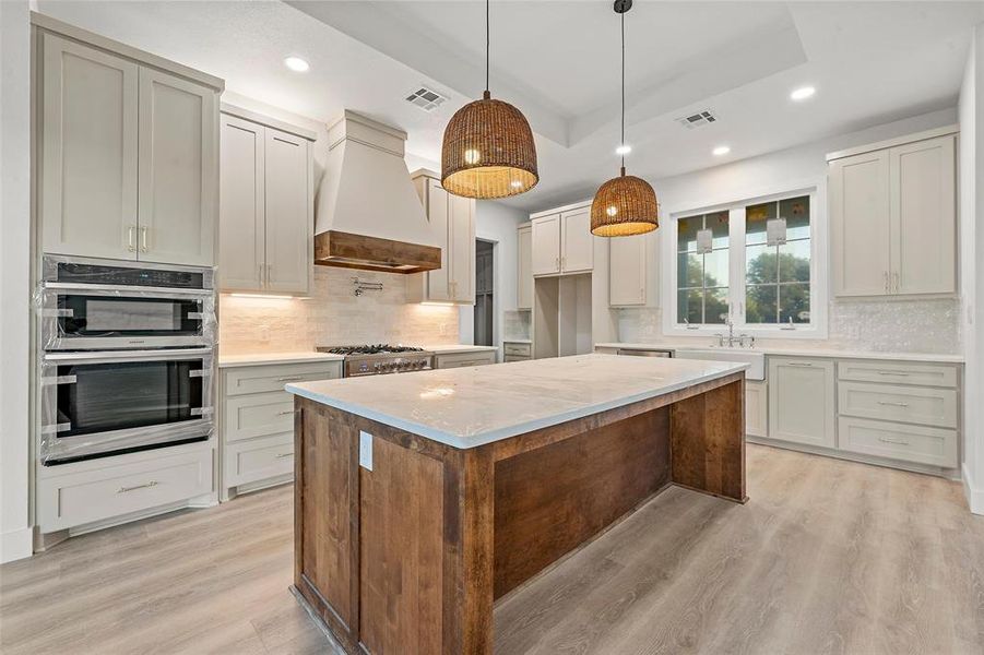 Kitchen with a center island, tasteful backsplash, light stone counters, stainless steel appliances, and recessed lighting Kitchen with a center island, tasteful backsplash, light stone counters, stainless steel appliances, and recessed lighting
