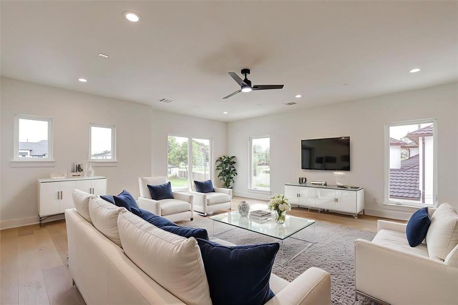 Living room with light wood finished floors, plenty of natural light, recessed lighting, and a ceiling fan