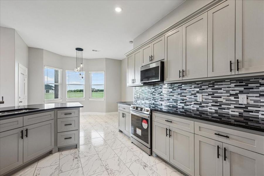 Kitchen with tasteful backsplash, light tile flooring, pendant lighting, sink, and appliances with stainless steel finishes