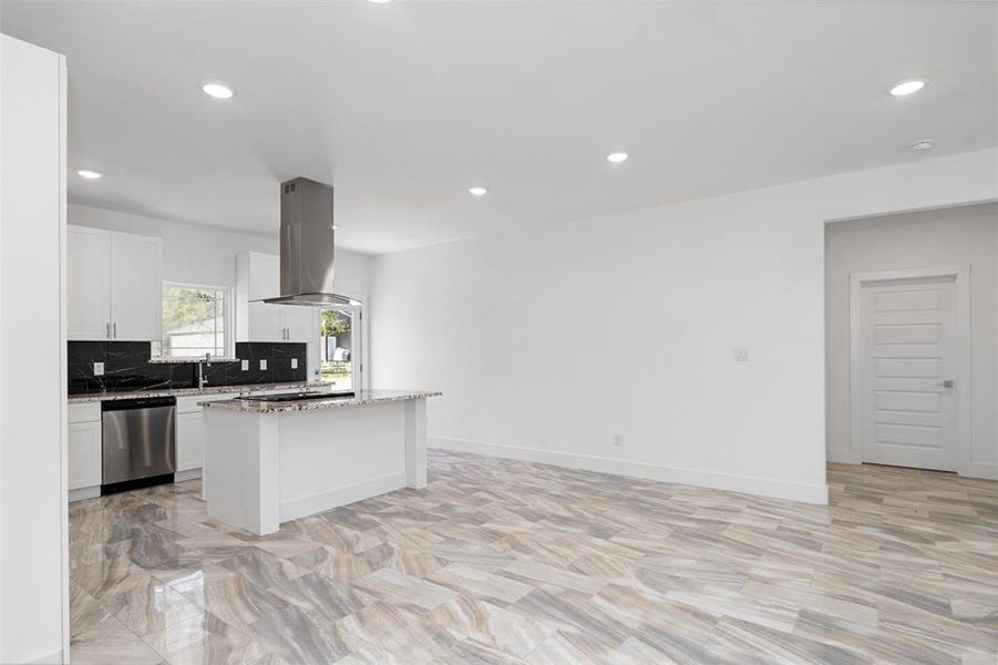 Kitchen featuring a center island, light stone counters, stainless steel dishwasher, island exhaust hood, and white cabinets