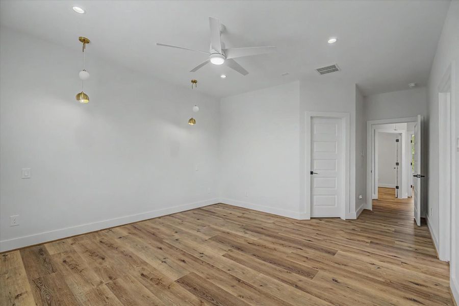 Primary bedroom featuring a remote-controlled ceiling fan, recessed can lighting, and dedicated bedside lighting.