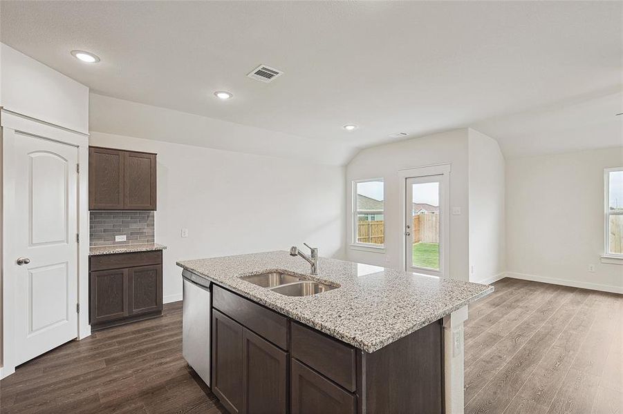 Kitchen with dark wood-type flooring, dark brown cabinets, sink, and a center island with sink