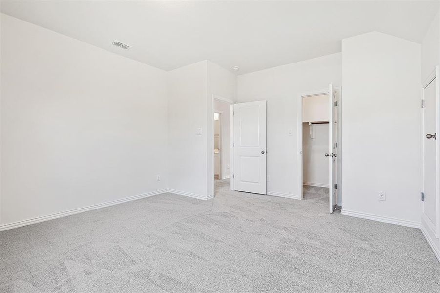 Unfurnished bedroom with a spacious closet, a closet, and light carpet