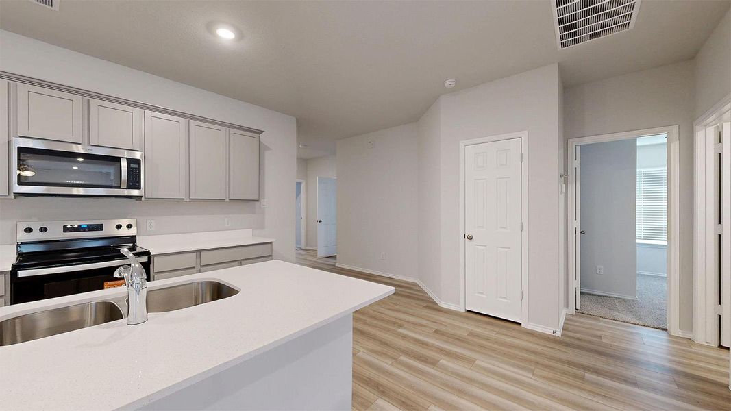 Modern kitchen with sleek stainless steel appliances and durable laminate flooring throughout.
