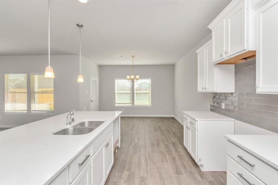 The heart of this home is its modern kitchen, featuring an expansive island with a built-in sink and plenty of counter space. The open layout allows for easy interaction with guests in the adjoining living and dining areas. With stylish pendant lights and sleek cabinetry, this kitchen is as beautiful as it is functional, making it perfect for both casual meals and formal gatherings. **This image is from another Saratoga Home with similar floor plan and finishes, not the June floorplan.**