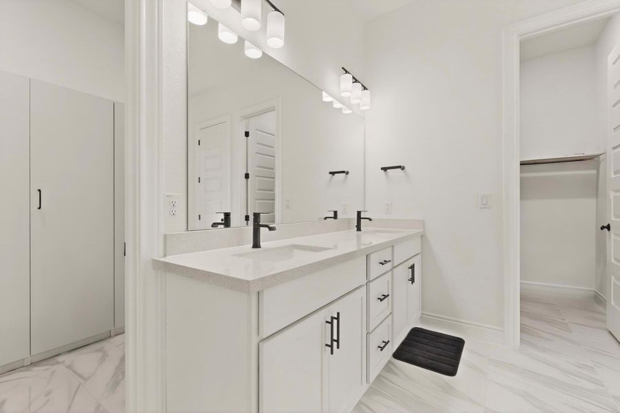 Full bath with double vanity, a walk in closet, and light marble finish flooring