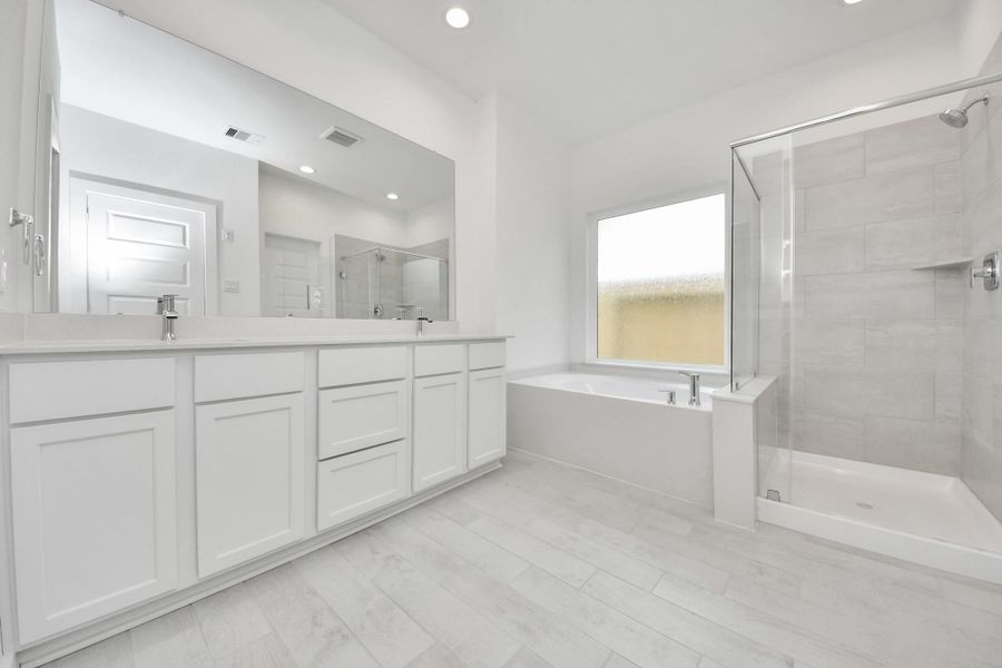 Escape to a spa-like oasis in this primary bathroom. Enjoy a walk-in shower with tile surround, a separate garden tub with custom detailing, and an elegant vanity featuring light countertops, modern hardware, and beautiful recessed lights. Experience luxury and relaxation in every detail. Escape to a spa-like oasis in this primary bathroom. Enjoy a walk-in shower with tile surround, a separate garden tub with custom detailing, and an elegant vanity featuring light countertops, modern hardware, and beautiful recessed lights. Experience luxury and relaxation in every detail.