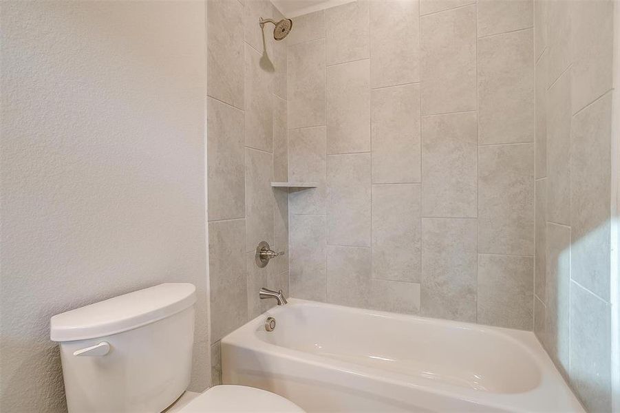 Bathroom with tiled shower / bath combo and toilet