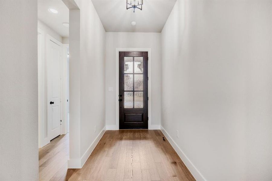 Foyer entrance with light wood-style flooring and hanging lights