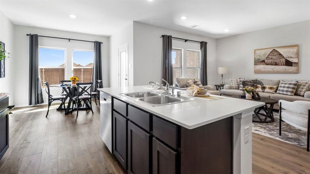 Kitchen with light countertops, open floor plan, an island with sink, light wood-style floors, and dishwasher
