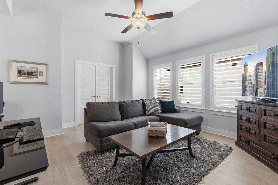Living area featuring light wood-style floors, vaulted ceiling, a ceiling fan, and a desk