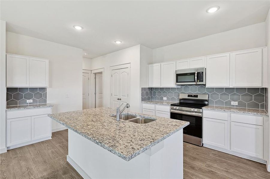 Kitchen with light wood-type flooring, sink, stainless steel appliances, and white cabinets