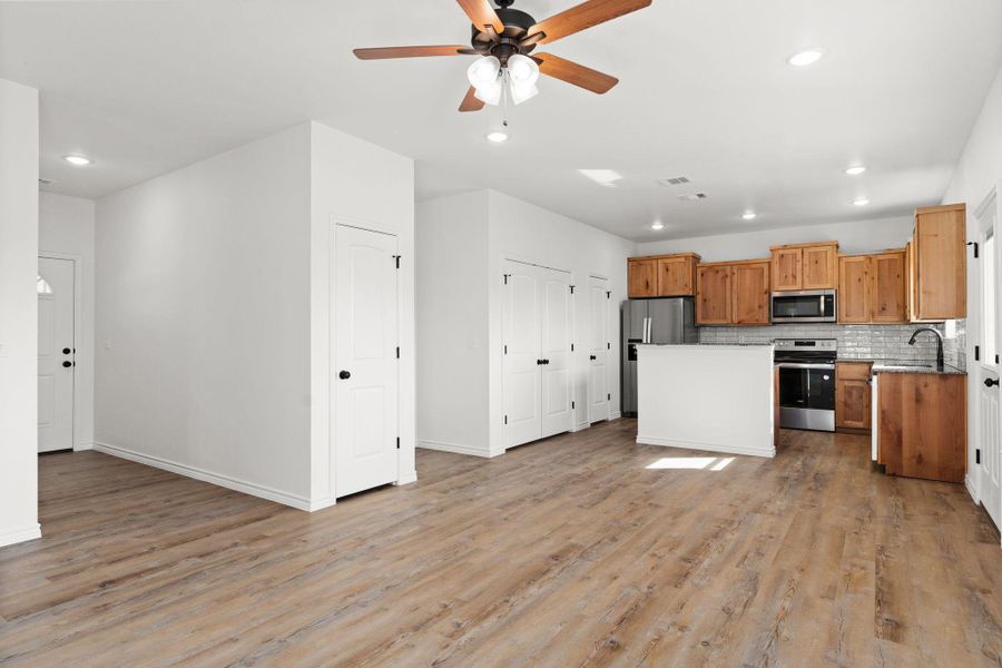 Kitchen with tasteful backsplash, a ceiling fan, appliances with stainless steel finishes, a sink, and open floor plan Kitchen with tasteful backsplash, a ceiling fan, appliances with stainless steel finishes, a sink, and open floor plan