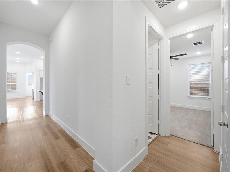 Hall with arched walkways, recessed lighting, and light wood-style flooring