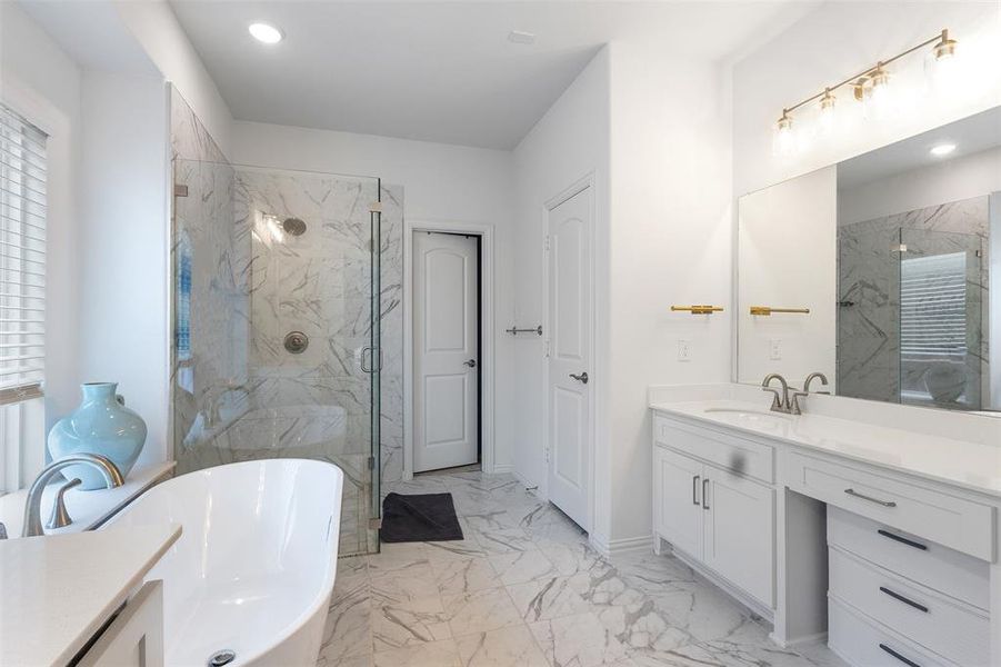 Full bath featuring a freestanding bath, light marble finish floors, a marble finish shower, vanity, and recessed lighting