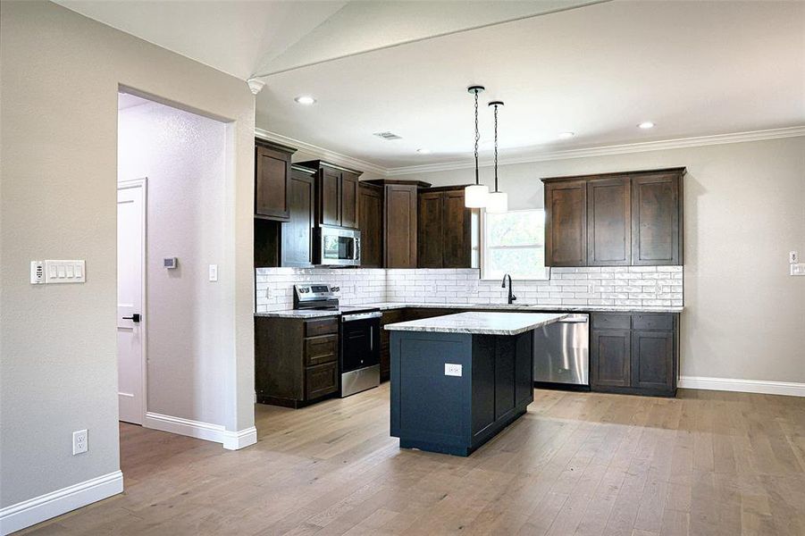 Kitchen with stainless steel appliances, granite countertops and decorative and under cabinet lighting.