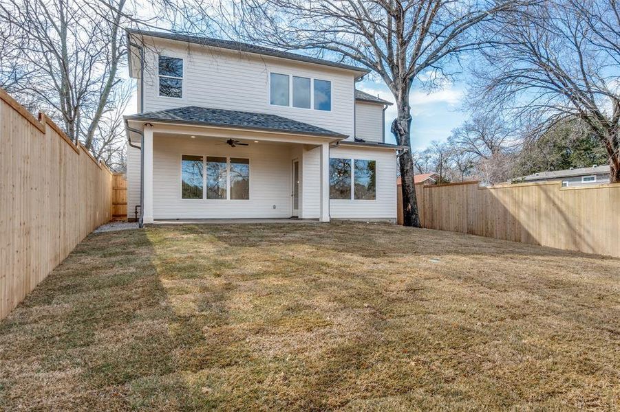 Rear view of house featuring a lawn and ceiling fan