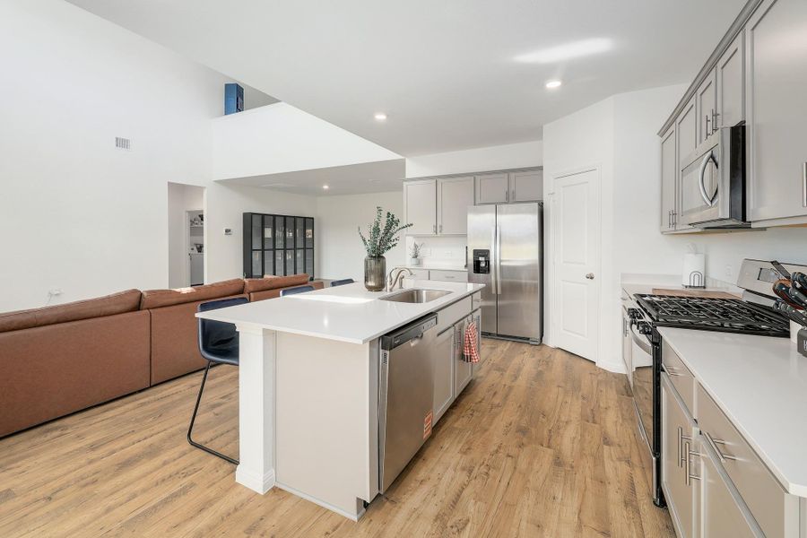 Open-concept kitchen featuring an island with an integrated sink and dishwasher, white countertops, and stainless steel appliances Open-concept kitchen featuring an island with an integrated sink and dishwasher, white countertops, and stainless steel appliances