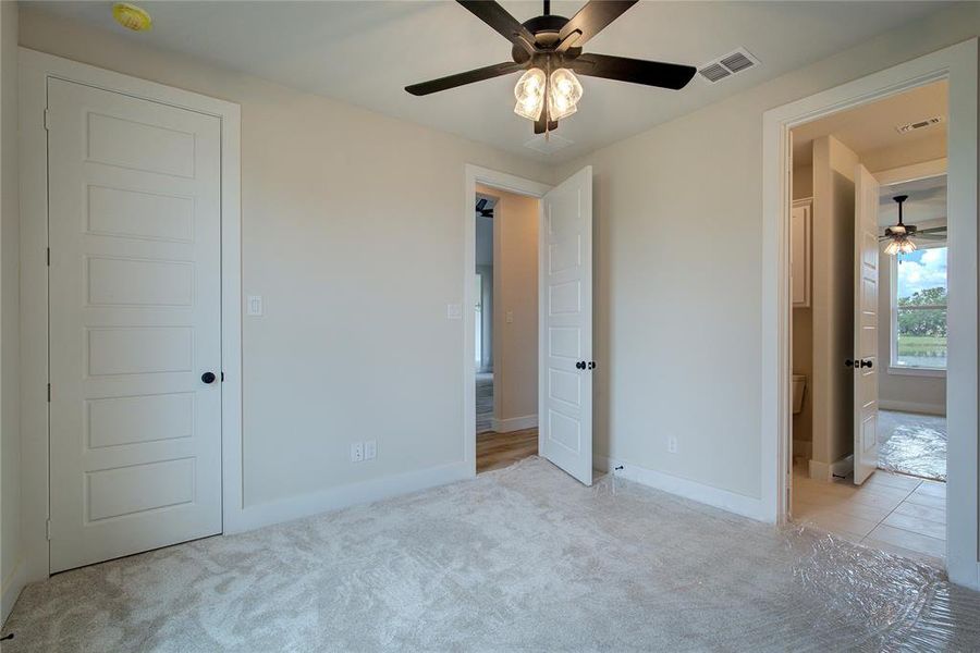 Unfurnished bedroom with light colored carpet and ceiling fan