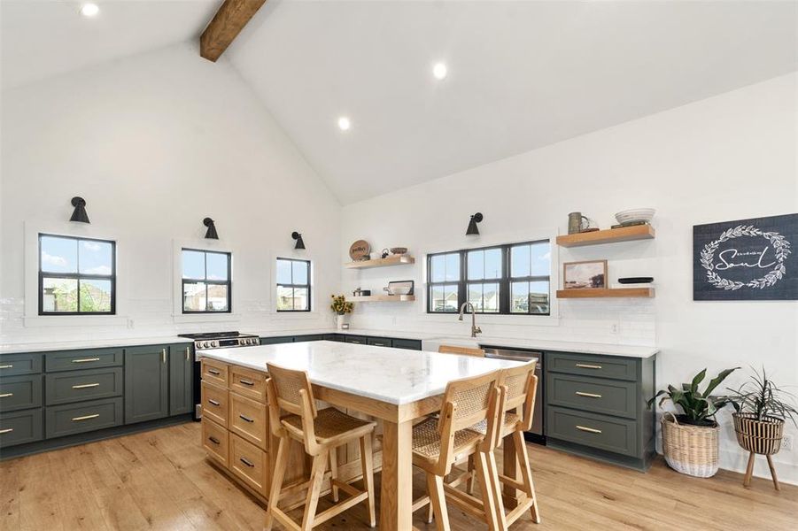 Kitchen with open shelves, appliances with stainless steel finishes, beamed ceiling, light wood-type flooring, and high vaulted ceiling