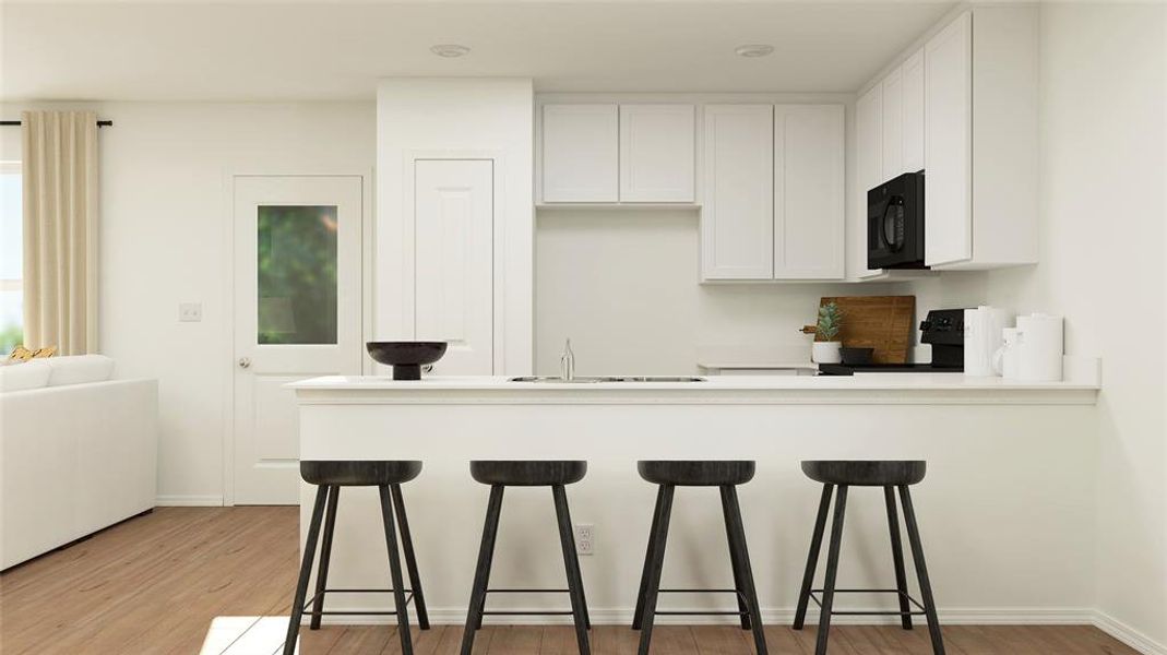 Kitchen with black microwave, a breakfast bar area, stove, light wood-type flooring, and a peninsula Kitchen with black microwave, a breakfast bar area, stove, light wood-type flooring, and a peninsula