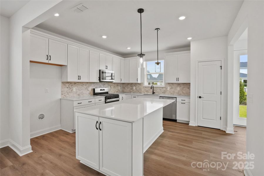 Bright kitchen with substantial storage, large island, quartz countertops, gas range, and more!