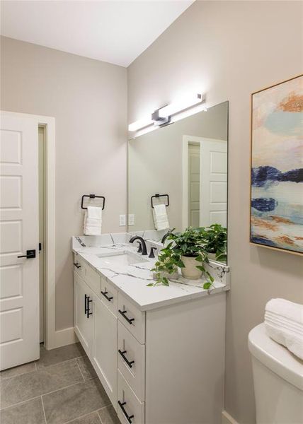 Bathroom featuring vanity with extensive cabinet space, toilet, and tile floors