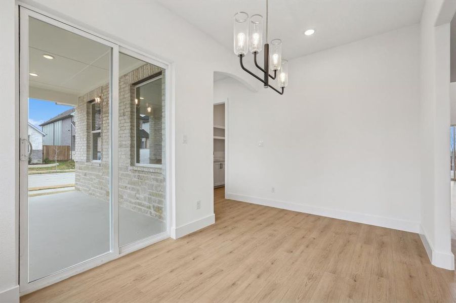 Unfurnished dining area with a chandelier and light wood-type flooring