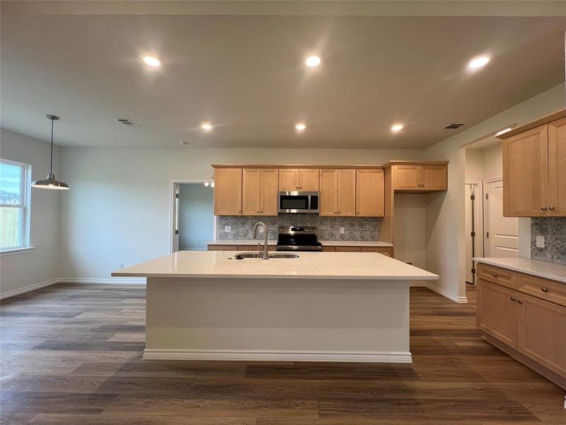 Kitchen featuring a kitchen island with seating; quartz Countertops; tile backsplash; double sink, soft-close shaker-style cabinets; stainless steel appliances & Walk-in Pantry