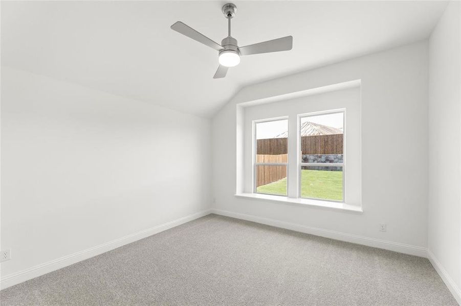 Carpeted spare room with ceiling fan and lofted ceiling