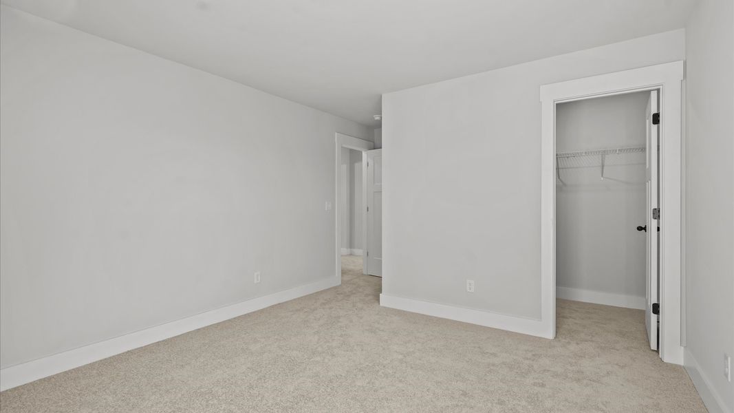Superior comfort in a secondary bedroom with plush carpet and an oversized walk-in closet