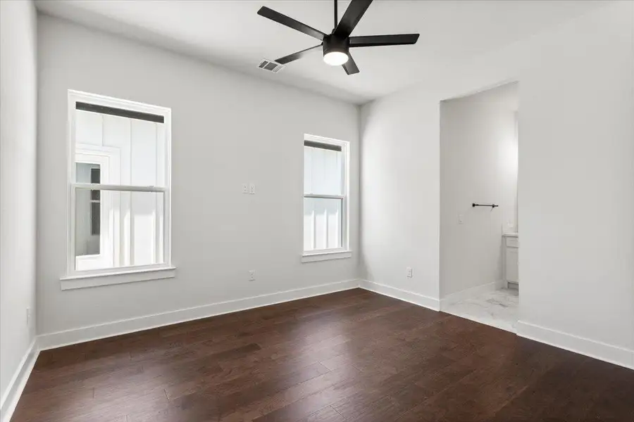 Unfurnished bedroom featuring wood finished floors, baseboards, ensuite bathroom, and a ceiling fan Unfurnished bedroom featuring wood finished floors, baseboards, ensuite bathroom, and a ceiling fan