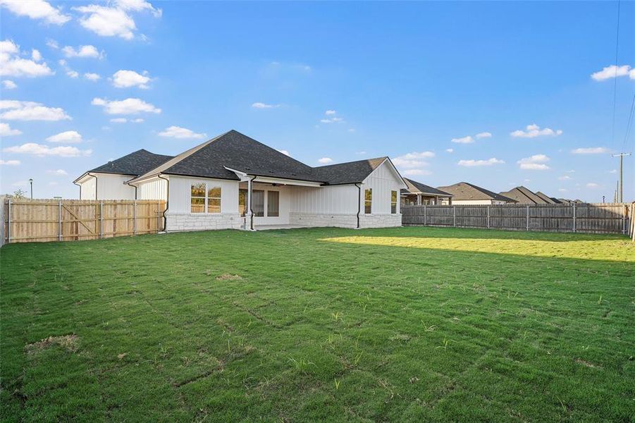 Back of property featuring a patio area, a fenced backyard, roof with shingles, and stone siding