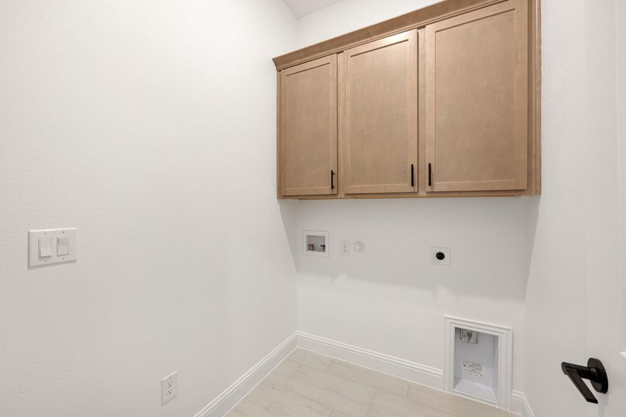 Laundry room with light wood upper cabinets, washer and dryer hookups, and tile floor