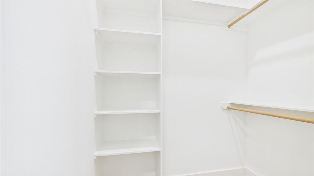 Walk-in closet featuring multiple shelves and hanging rods, perfect for organized storage.