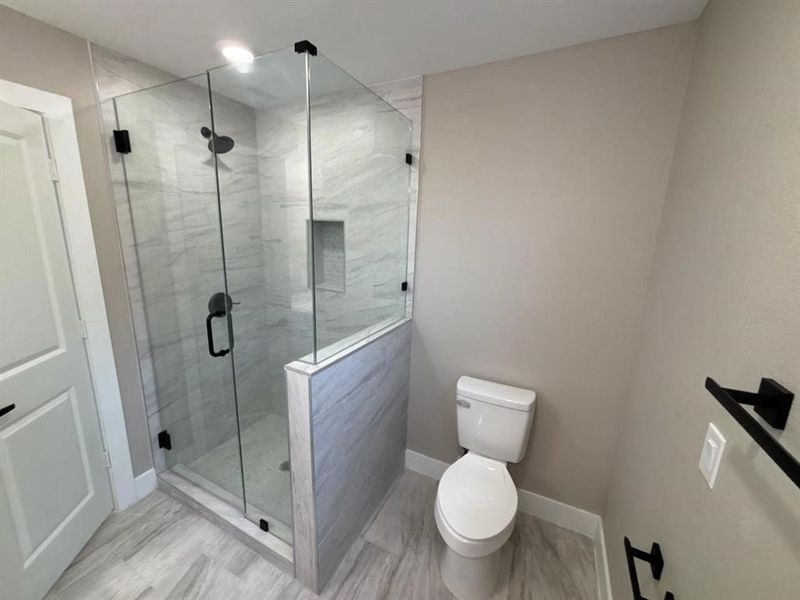Full bathroom featuring a stall shower and toilet Full bathroom featuring a stall shower and toilet