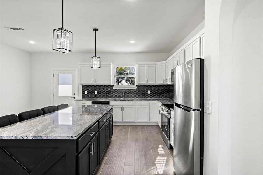 Kitchen with backsplash, dark cabinets, dark stone counters, stainless steel appliances, and white cabinetry
